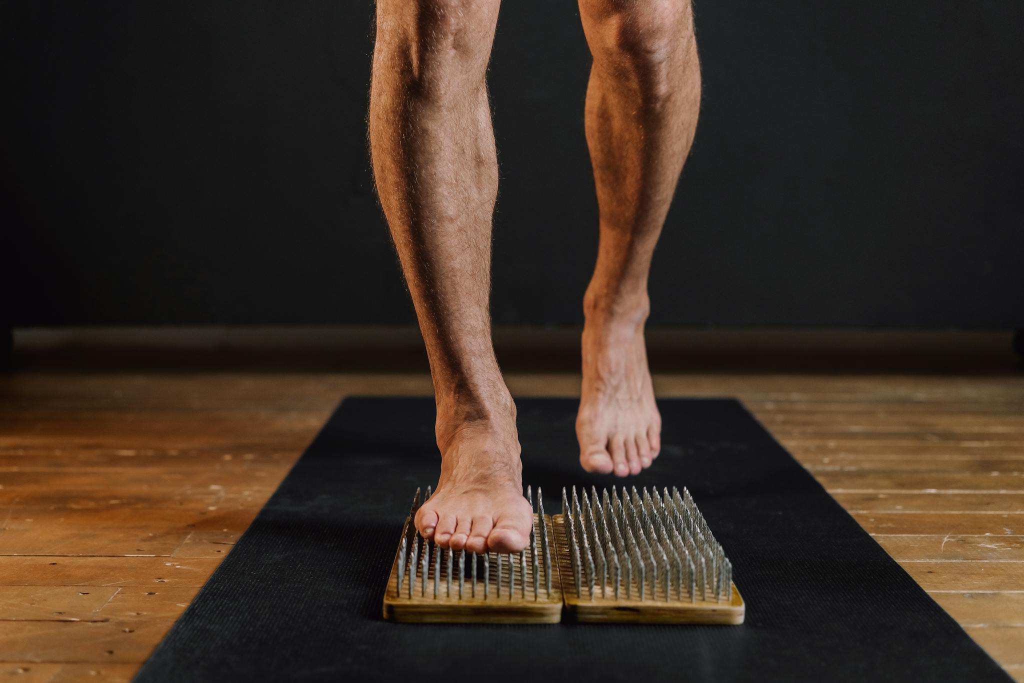 A person balances on a wooden nail board, demonstrating focus and mindfulness.