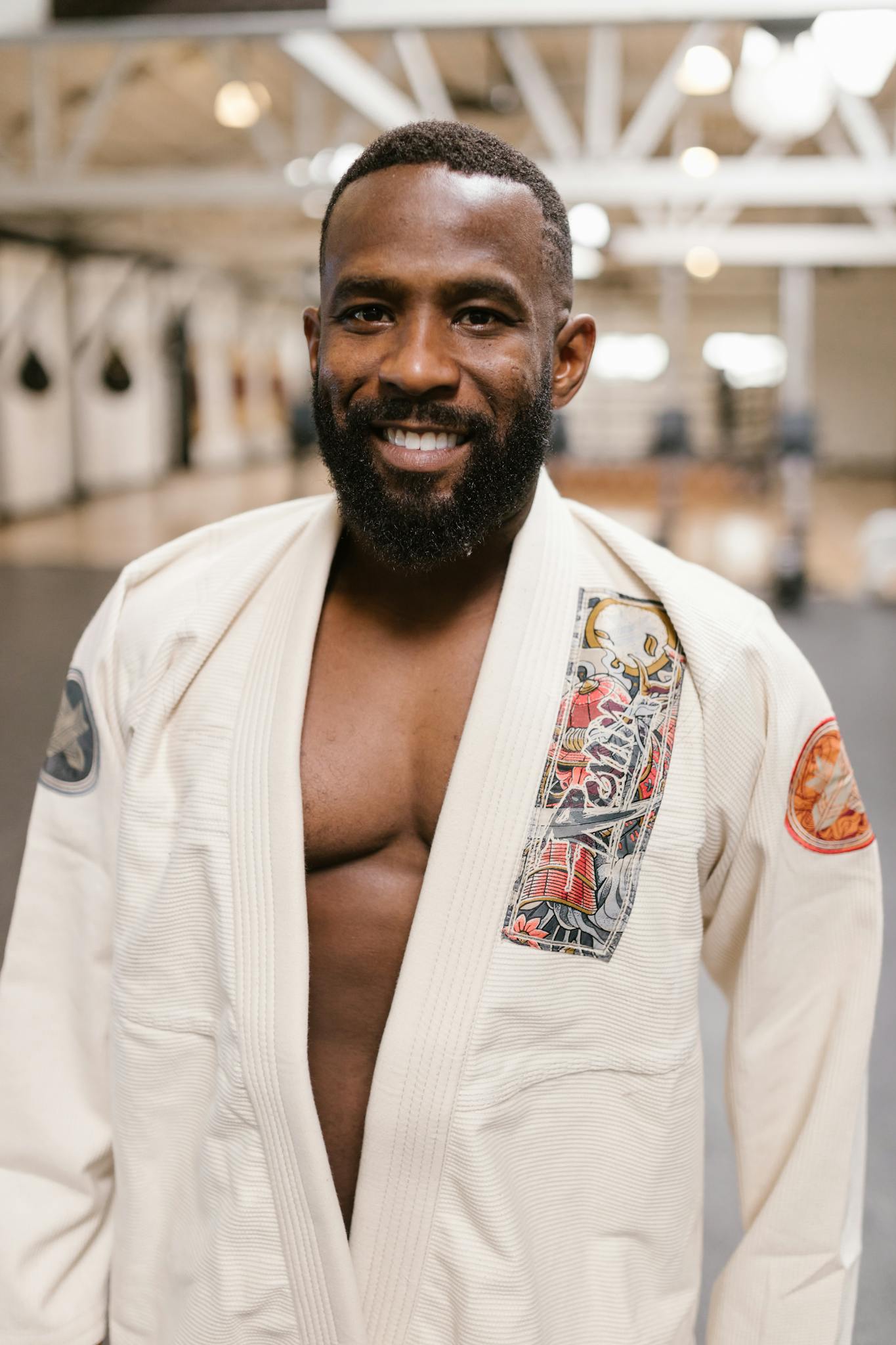Smiling man wearing a martial arts uniform inside a gym, conveying strength and happiness.
