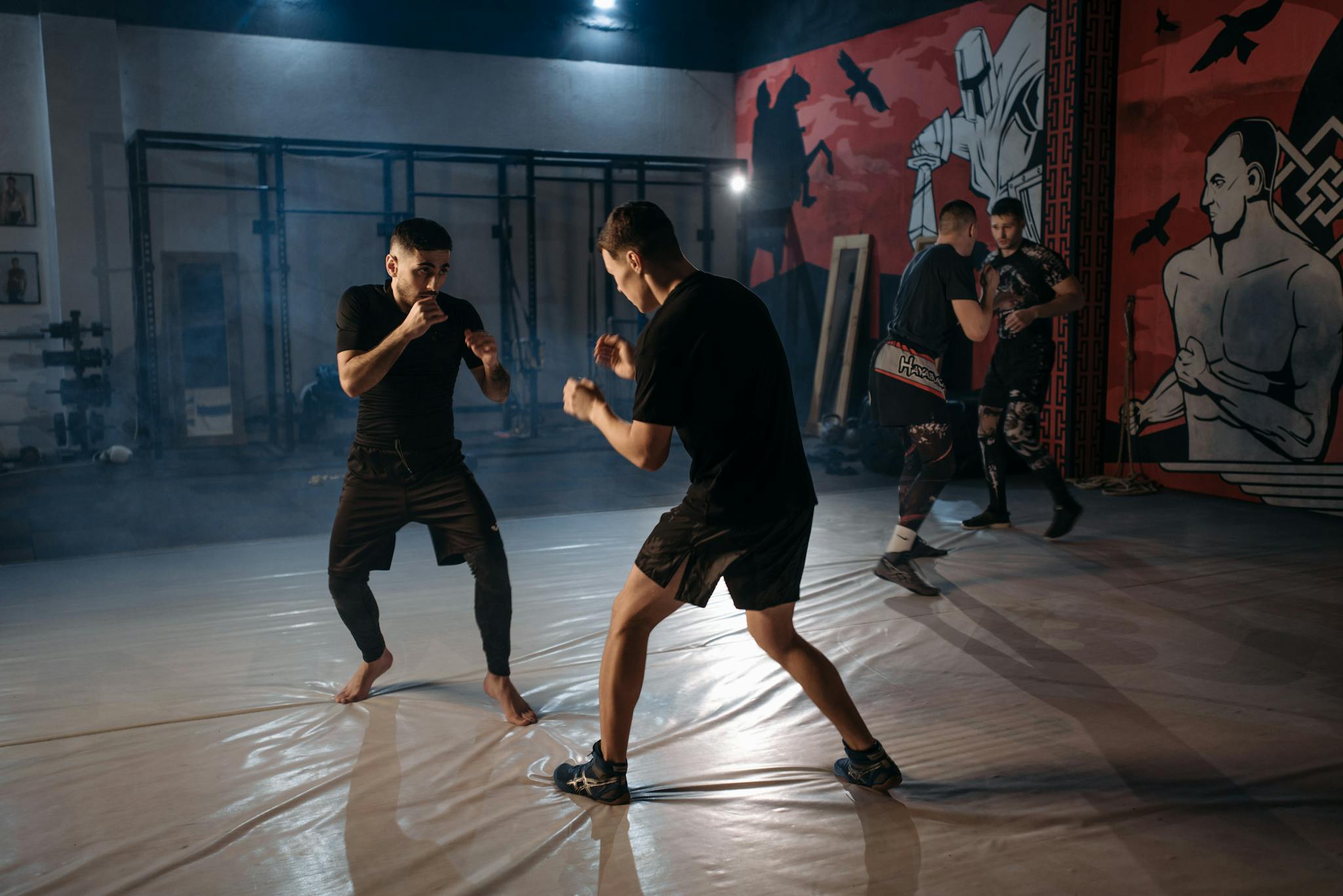 Two martial artists sparring intensely during an indoor training session.